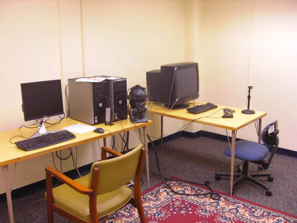 desks with computers and a TV next to a bust of a human head